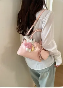 Detail of light pink leather shell bag with bear charm and heart pouch carried by model