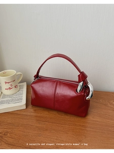 Close-up of a vintage dark red handbag with polished finish and silver chain decor