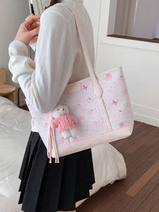 Pink printed tote bag with bow patterns and teddy bear charm shown on model