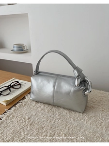 Detail of silver handbag with metallic texture and industrial chain on plush mat