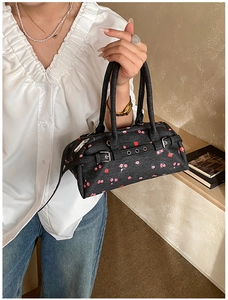 Close-up of floral denim bowling bag with leather straps and silver metal buckles