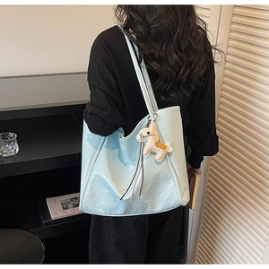 Detail of light blue wrinkled leather tote bag with a beige horse charm on shoulder