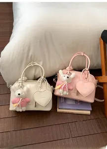 Detail of elegant shell handbag with heart charm and plush sheep pendant in cream and pink