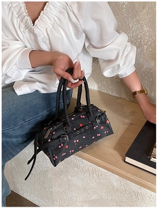 Detail view of denim bowling bag featuring red floral print and silver eyelet accents