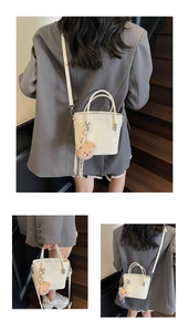 Macro shot of white bucket bag with leather texture and cute brown teddy bear charm