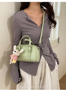 Detail of light green retro leather handbag with knit rabbit charm on a model outfit