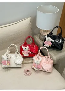 Collection of shiny shell bags in four colors with cute rabbit charms on a sofa