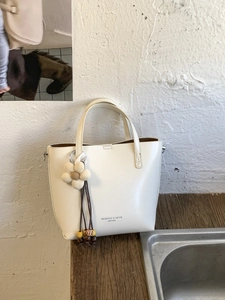 Elegante borsa sottobraccio in pelle crema con ciondolo floreale e manici
