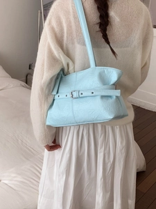 Fashionable light blue pleated leather tote bag with silver buckle worn by a model
