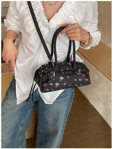 Detail of floral denim bowling bag with silver buckles and adjustable shoulder strap
