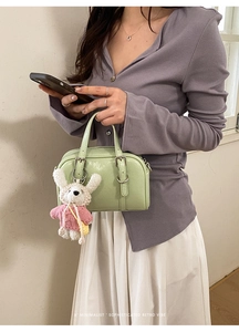 Detail of mint green Boston bag with adjustable strap and cute white bunny plush charm