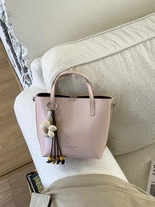Elegante borsa a secchiello in pelle rosa cipria con ciondolo a fiore e nappa