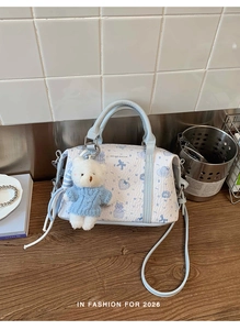 Detail der süßen Katzen-Print-Tasche mit blauem Teddybär-Anhänger auf Holzoberfläche