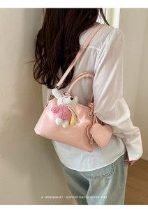 Detail of pink shell bag with heart-shaped pouch and plush bear charm on a model