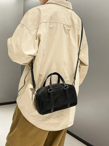 Minimalist black matte boston handbag with dual handles and crossbody strap on a model