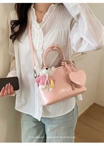 Detail of pink shell bag with heart coin purse and white teddy bear charm on strap