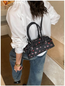 Detailed view of dark blue denim barrel bag with pink floral print and metal buckle