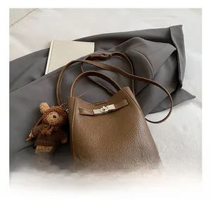 Detail of dark brown pebble leather bucket bag with silver lock and bear charm