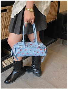 Detail of light blue denim bowling bag with red floral pattern and silver hardware