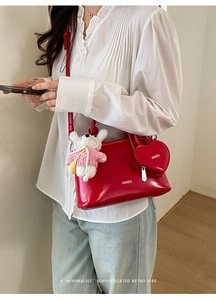 Detail of red patent leather shell bag with heart coin purse and plush bear charm