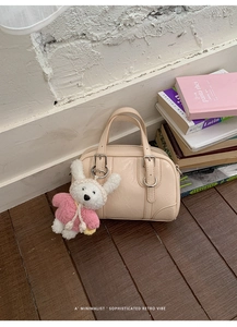 Detail of cream faux leather handbag with silver hardware and cute plush bunny charm