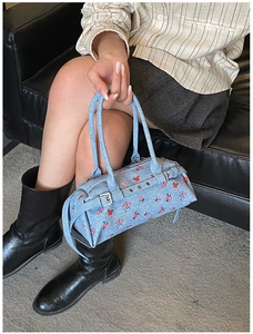 Detail of light blue denim bowling bag with red floral pattern and silver buckle hardware