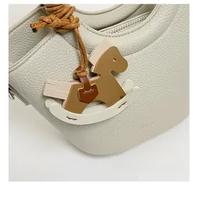 Detail der Leder-Beuteltasche mit buntem Schaukelpferd-Anhänger und Markenlogo