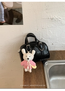 Detail of black patent leather Boston bag with a cute plush bunny charm and silver buckle