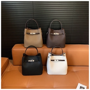 Close-up of four colors of lychee grain leather bucket bags on a premium leather sofa