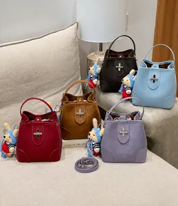 Detail view of colorful leather bucket bags with cross metal buckles and bear pendants