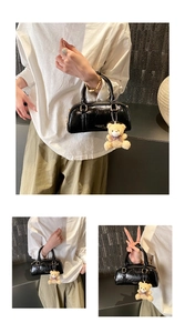 Detailed view of a black glossy cylinder handbag with a cute plush bear charm accessory