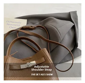 Detail of dark brown lychee leather bucket bag with silver turn-lock and adjustable strap