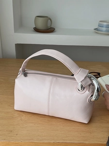 Minimalist light pink leather handbag with silver ring handle detail on wood table