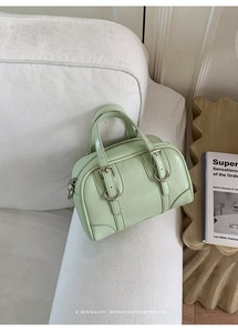 Detail of mint green leather mini Boston bag with silver hardware on white sofa