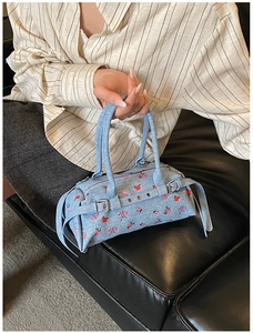 Detail of light blue floral denim bowling bag with red flower patterns and silver studs