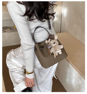 Detailed side view of vintage leather bucket bag with cute teddy bear charm and strap