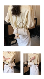 Three-way view of a cream Boston bag with a teddy bear charm in a home setting