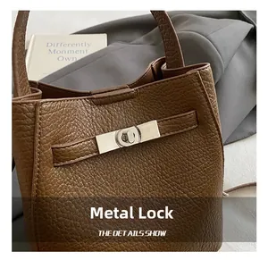 Detail of silver metal clasp on brown lychee-patterned leather bucket bag