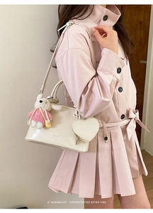 Detail of cream shell handbag featuring a heart pouch and knitted rabbit charm