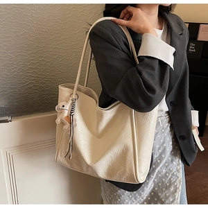 Detail of cream tote bag in wrinkled glossy leather with a horse-shaped pendant