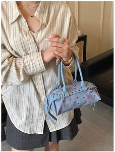 Detail of light blue denim tote bag with red floral print and silver metal buckle hardware