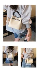 Detail of cream bucket bag featuring leather handle, turn-lock closure and bunny charm