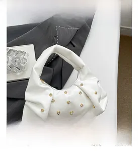 Detail of white pleated handbag featuring gold studs and elegant metal chain strap