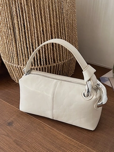 Minimalist cream cylinder handbag with leather texture and silver chain strap details