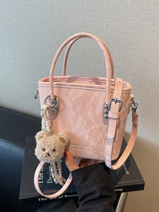 Pink bucket bag with marble texture, crossbody strap, and plush bear charm decoration