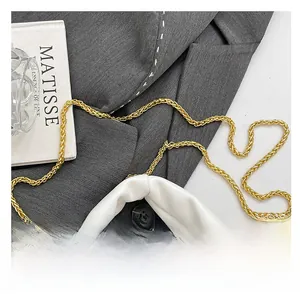 Detail of white leather handbag featuring elegant gold metal chain strap and rivet accents