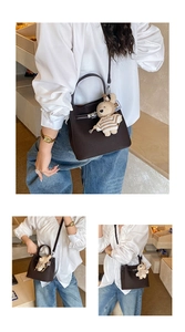Detail of dark brown bucket bag with lychee texture and cute bear pendant accessory