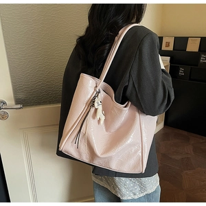 Pink glossy tote bag with cartoon dog charm shown on shoulder for a stylish commuter look