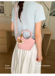 Detailansicht der rosa Beuteltasche aus Leder mit Rundgriff und hölzernem Anhänger