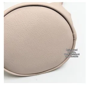 Detail of the reinforced round base on a beige leather bucket bag with pebble texture